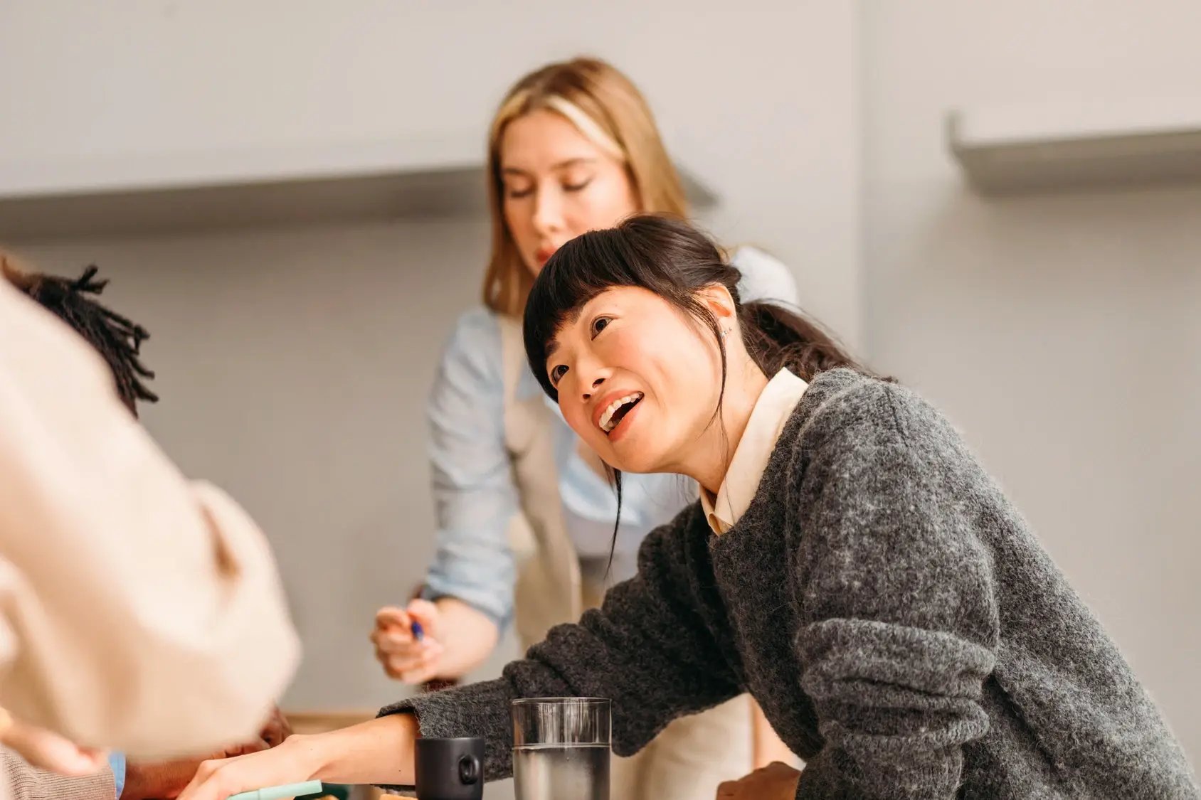 Woman leaning forward and speaking animatedly while collaborating with colleagues at a table.